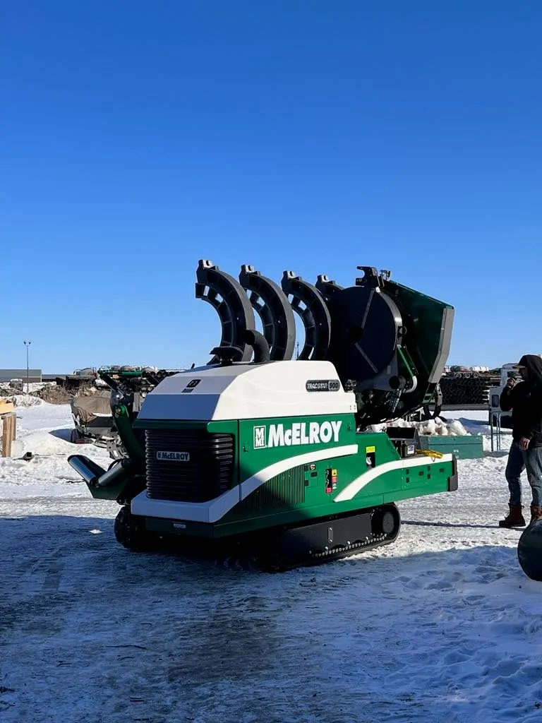 White and green McElroy tracked fusion machine on a snowy jobsite